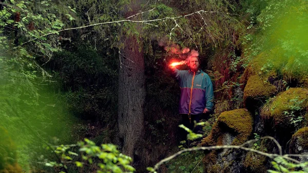 Smoking red signal fire. Stock footage. Traveler stuck and lost in woods lit red fire signal for rescue. Lost during hike in woods, man lit signal flare and waving to to be found