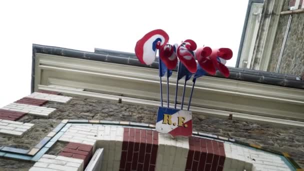 Widok dolny wiszących flag. Działania. Flagi powiesić i huśtawka nad łuku znaczącego budynku miasta. Widok z dołu skręconych flag wiszących — Wideo stockowe