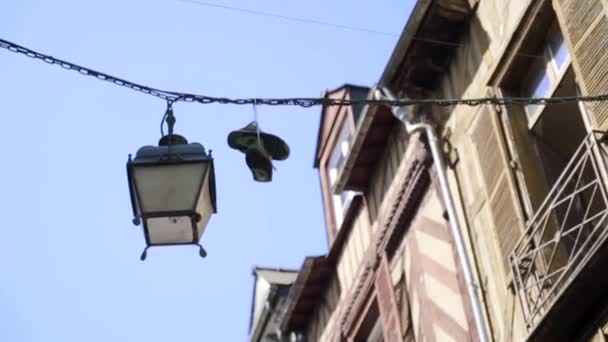 Las zapatillas están colgadas de cables. Acción. Zapatillas colgando de cables en el fondo de la casa y el cielo azul. Los matones habían colgado un par de zapatillas en el cable de la calle — Vídeos de Stock