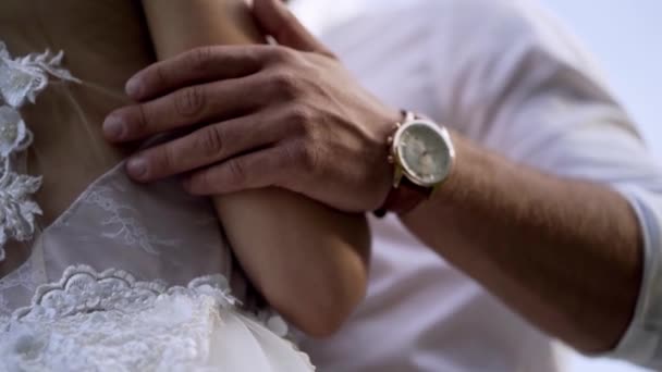 Κοντινό-up των συζύγων χέρια αγκαλιάζοντας τη γυναίκα. Δράση. Ο σύζυγος αγγίζει απαλά τη μέση των συζύγων του σε λευκό νυφικό. Έννοια του γάμου — Αρχείο Βίντεο