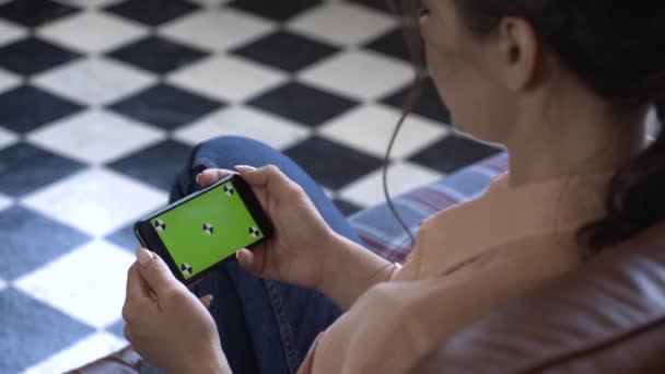 Primer plano de la mujer joven con camisa rosa sosteniendo su teléfono inteligente horizontalmente y tocando en la pantalla verde clave de hroma. Imágenes de archivo. Pantalla de clave de croma para la colocación de su propio contenido . — Vídeo de stock