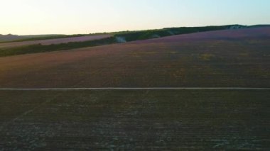 Şafakta kırsal alanlardan geçen yol. Atış. Şafakvakti karanlık çiftlik alanlarının güzel kırsal manzara üst görünümü. Güneşin ilk ışınları kırsal alanda çalışan çorak yol üst görünümü