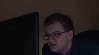 Genç adam sinirli geceleri bilgisayar başında çalışır. Stok görüntüleri. Yorgun ve sinirli işçi geceleri ofiste bilgisayar başında çalışamaz