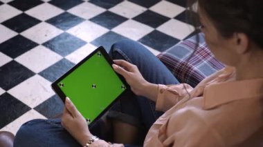Sandalyede oturan ve renk anahtar yeşil ekran ile tablet dokunarak güzel genç kadın yakından görünümü. Stok görüntüleri. Kendi içeriğinizin yerleştirilmesi için Renk anahtar ekranı.