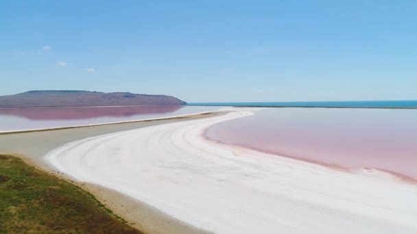 クリミアのオレンジ湖ショット。白い砂に対する明るいオレンジ色の湖の水のトップビュー。青空を背景に白い砂の上にカラフルなオレンジ色の水の地球外の風景 — ストック動画