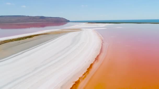 Lago laranja na Crimeia. Atingido. Vista superior da água do lago laranja brilhante contra a areia branca. Paisagem extraterrestre de água laranja colorida na areia branca no fundo do céu azul — Vídeo de Stock