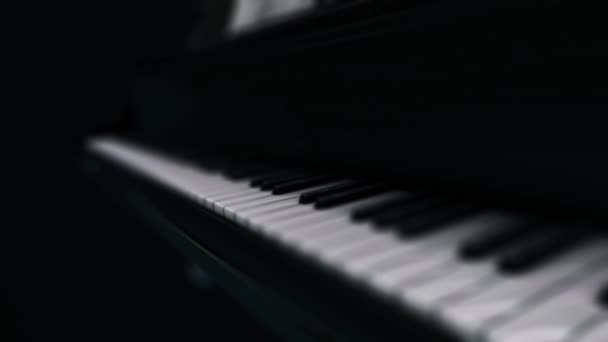Κινούμενα σχέδια του πολυτελούς μαύρου πιάνου με λευκά θολά κλειδιά στο σκοτάδι. Κινούμενα σχέδια. απεικόνιση απόδοσης 3D. κινούμενα σχέδια 4K. — Αρχείο Βίντεο