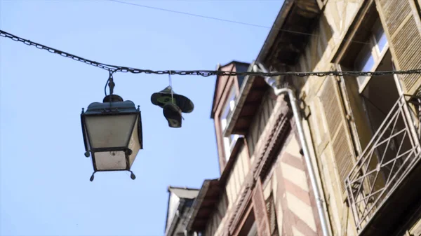 Les baskets sont accrochées aux fils. L'action. Baskets suspendues à des fils de câble sur fond de maison et de ciel bleu. Des brutes avaient accroché une paire de baskets sur du fil de la rue — Photo