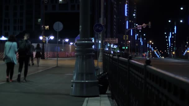 Luci della città di notte sulla carreggiata. Filmati delle scorte. La città di notte è bella in luci al neon su strada. Camminando di notte d'estate la gente cammina su marciapiede alla luce di lanterne — Video Stock