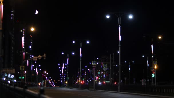 Luces de la ciudad por la noche en la carretera. Imágenes de archivo. La ciudad nocturna es hermosa en luces de neón en la carretera. Noche de verano en la ciudad iluminada por la tenue luz de las linternas en el camino vacío — Vídeos de Stock