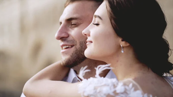 Close-up de jovens e adoráveis recém-casados beijando. Acção. Sorrisos sinceros e radiantes de noiva e noivo iluminados pelo sol. Conceito de amor — Fotografia de Stock