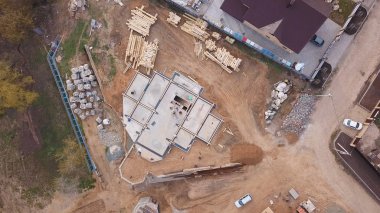 Inşaat malzemeleri ahşap panoları, kayalar, tuğla ve inşaat alanında çalışan ve beton dökme insanlar yukarıdan görünümü. Klip. Yeni bina yapım süreci
