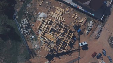 Devam eden yeni ahşap yazlık bina, inşaat makineleri, işçiler ve inşaat malzemeleri yaz günü yukarıdan görünümü. Klip. Yeni bina yapım süreci.