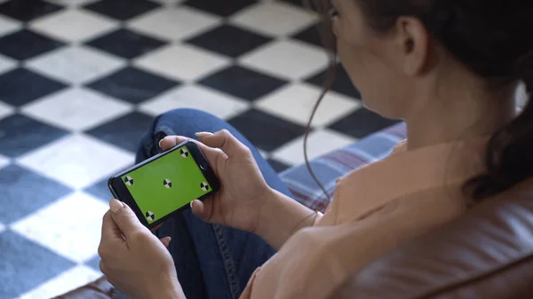 Primer plano de la mujer joven con camisa rosa sosteniendo su teléfono inteligente horizontalmente y tocando en la pantalla verde clave de hroma. Imágenes de archivo. Pantalla de clave de croma para la colocación de su propio contenido . — Foto de Stock