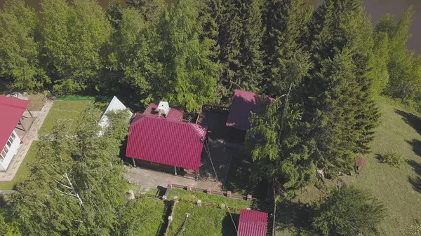 Vista aérea de hermosas casas de campo modernas con techos rojos cerca del bosque de coníferas verdes en el cálido día de verano. Clip. Tiempo encantador para vacaciones fuera de la ciudad — Foto de Stock