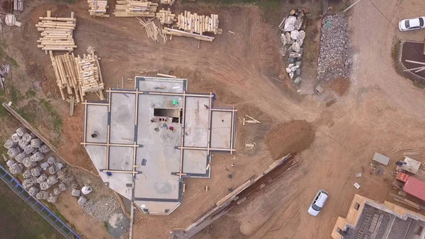 Şantiye nin havadan görünümü ve inşaat malzemelerinin yakınındaki yeni evin veya atölyenin temeli için beton döken işçiler. Klip. Yeni bina yapım süreci.