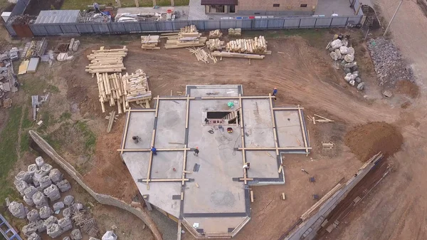 Şantiye nin havadan görünümü ve inşaat malzemelerinin yakınındaki yeni evin veya atölyenin temeli için beton döken işçiler. Klip. Yeni bina yapım süreci.