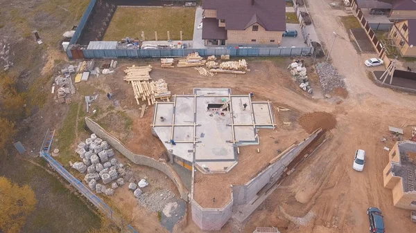 Inşaat malzemeleri ahşap panoları, kayalar, tuğla ve inşaat alanında çalışan ve beton dökme insanlar yukarıdan görünümü. Klip. Yeni bina yapım süreci