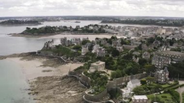 Gri bulutlu gökyüzüne karşı yaz aylarında nehir yakınında gri eski Avrupa kenti ve parlak yeşil bitki örtüsü kontrast havadan görünümü. Eylem. Güzel Avrupa mimarisi