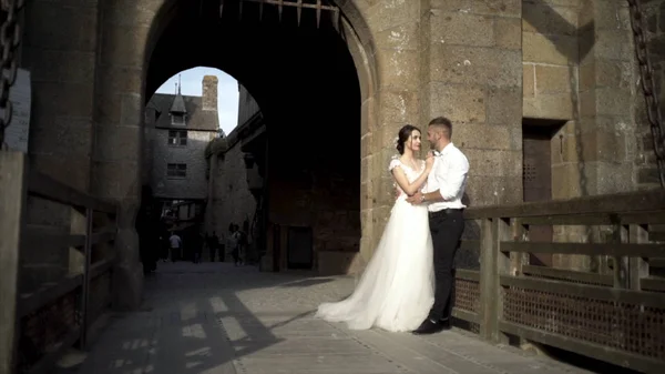 Yeni evliler, ortaçağ kalesinin arka planında yer almaktadır. Eylem. Güzel gelin ve damat ortaçağ kale ayakta göz birbirlerine bakmak. Düğün konsepti — Stok fotoğraf