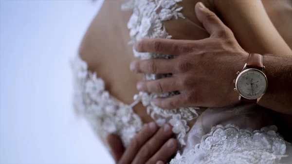 Primo piano di mariti che abbracciano moglie. Azione. Marito tocca delicatamente la sua vita mogli in abito da sposa bianco. Concetto di matrimonio — Foto Stock