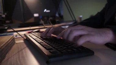 Klavyede yazan hacker'ın yakın çekim. Stok görüntüleri. Programcı bilgisayar klavyesinde hızlı bir şekilde kod veya metin yazar. Lamba ışığında mens eller gece bilgisayara kesmek
