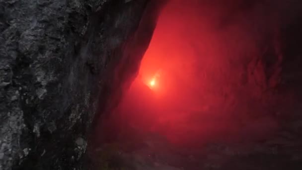 Reiziger in Dark Cave. Stock footage. Man met rode toorts gaat door smalle tunnels van Dark Cave. Gevaarlijke en fascinerende verkenning van passages in Rock Cave — Stockvideo
