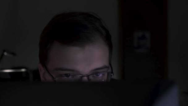 Κοντινό του νεαρού προγραμματιστή που κοιτάζει προσεκτικά την οθόνη. Υλικό από μετοχές. Νέος ελκυστικός εργαζόμενος γραφείο εργάζεται αργά το βράδυ σε αναφορές φινίρισμα υπολογιστή — Αρχείο Βίντεο