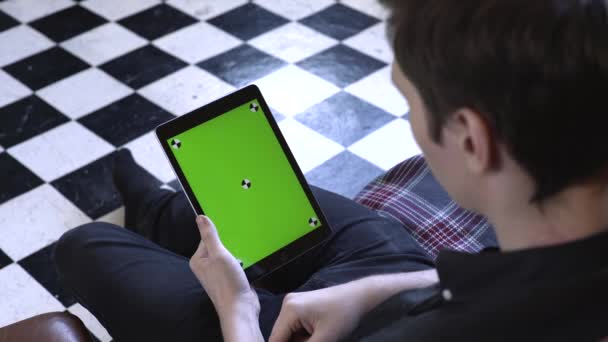 Uitzicht vanaf de schouder van de jonge man in zwart shirt met behulp van groene mock-up scherm digitale tablet computer in liggende modus. Stock footage. Chroma Key-scherm voor het plaatsen van uw eigen inhoud. — Stockvideo