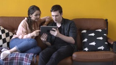 Evde kanepede oturan ve tablet ekranına izlerken mutlu genç çift in yakın çekim görünümü. Stok görüntüleri. Erkek ve kadın kanepede rahatlatıcı, mutlu hafta sonu