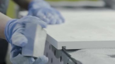 Yakın çekim işçi el parlatma ahşap tahta. Eylem. Eldivenli işçi, zımpara tahtası tahta sını parlatmak. Whetstone yaygın ahşap yüzeylerin manuel taşlama için kullanılır