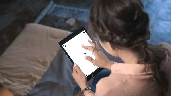 Vista superior de la mujer joven con el pelo castaño sentado en la silla, sosteniendo el iPad, escribiendo y deslizándose en la pantalla blanca croma clave. Imágenes de archivo. Concepto de nueva tecnología Smartphone — Foto de Stock
