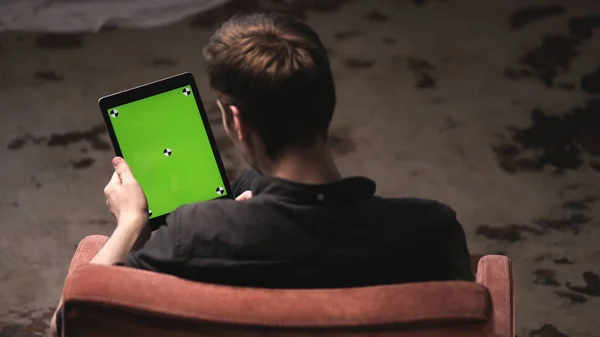 Man with brown hair in black shirt sliding on green mock-up screen of digital tablet computer with tracking marks. Stock footage. Chroma key screen for placement of your own content.