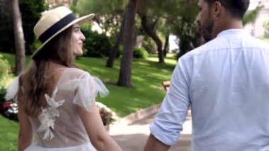 Parkta kulpla yürüyen genç bir çift sevgili. Eylem. Güzel bir çift yeşil parkta yürürken konuşuyor. Romantik yaz yeşil parkta sevdiğiniz ile el ele tutuşarak yürüyor