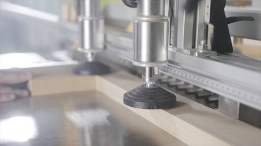 Marangoz matkaplar ile endüstriyel makine üzerinde çalışıyor. Eylem. Ahşap tahta delikler yapan endüstriyel makine üzerine sabitlenir. Ahşap işletmede profesyonel ekipmanlar