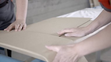 İşçilerin yakın çekim düz paket paketlenmiş. Eylem. Tulum işçileri eve teslim için fabrikadan yapı malzemesi paketi. Yapı malzemeleri veya mobilyadoğrudan fabrikadan teslim edilir