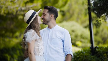 Güzel genç çift birbirlerine hayran. Eylem. Yeni evliler birbirlerine karşı kucaklaşmak ve nazik bakışlar atmak standı. Çift balayı yeşil park karşı kucaklama standı
