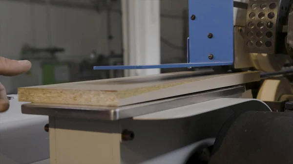 Close-up of moving machine with wooden boards. Action. Close-up of board moving on tape machine in industrial enterprise. Automated modern equipment for wooden products