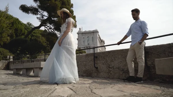 Schönes junges Paar auf Hochzeitsreise. Aktion. Ehemann bewundert seine schöne junge Frau, die im weißen Kleid wirbelt. Frischvermählte vor dem Hintergrund der steinernen Aussichtsplattform — Stockfoto