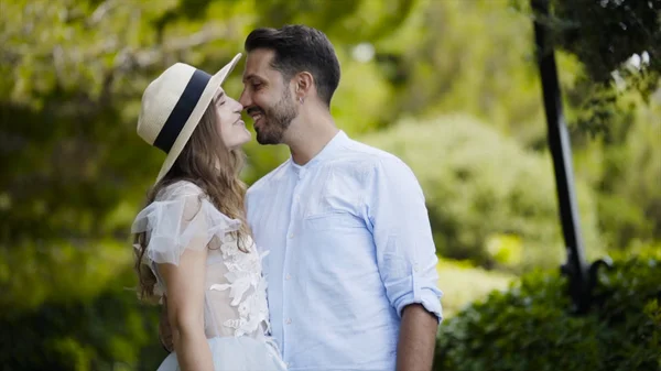 Bella giovane coppia che si ammira. Azione. Gli sposi si abbracciano l'uno contro l'altro e gettano dolci sguardi. Coppia stand in abbraccio contro parco verde in luna di miele — Foto Stock