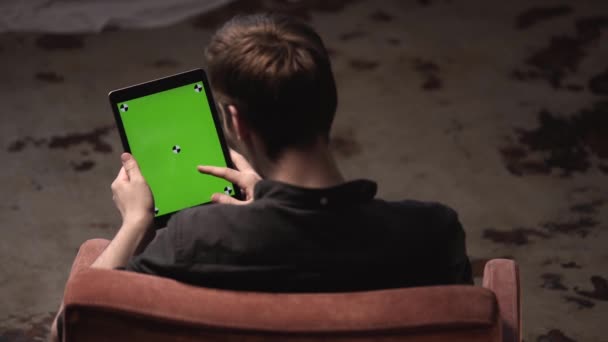 Man med brunt hår i svart skjorta glidande på grön mock-up skärm av digital Tablet PC med spårnings märken. Stock film. Chroma Key Screen för placering av ditt eget innehåll. — Stockvideo