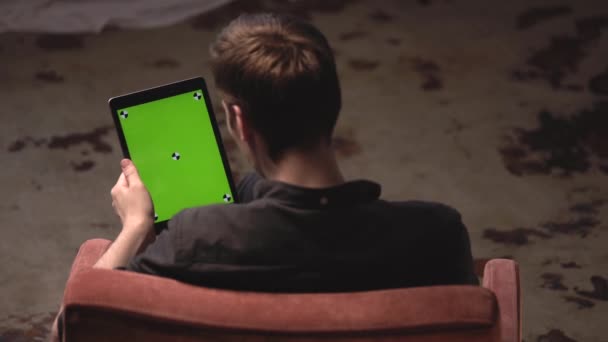 Man med brunt hår i svart skjorta glidande på grön mock-up skärm av digital Tablet PC med spårnings märken. Stock film. Chroma Key Screen för placering av ditt eget innehåll. — Stockvideo