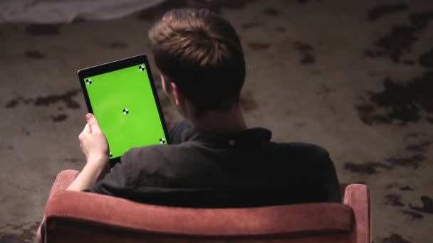 Uomo con capelli castani in camicia nera scorrevole su schermo mock-up verde di computer tablet digitale con segni di tracciamento. Filmati delle scorte. Schermata chiave cromatica per il posizionamento dei propri contenuti . — Video Stock