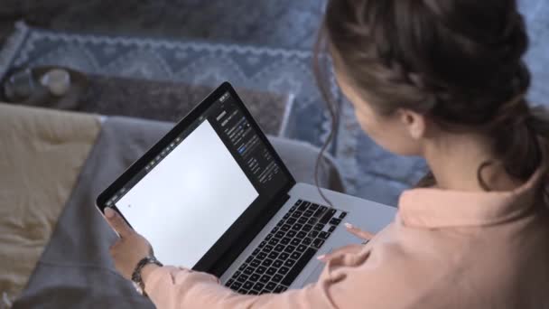 Vista superior de mujeres jóvenes en camisa rosa trabajando en su computadora portátil y escribiendo texto en algún programa con pantalla de espacio en blanco. Imágenes de archivo. Hermosa mujer joven que trabaja en casa — Vídeo de stock