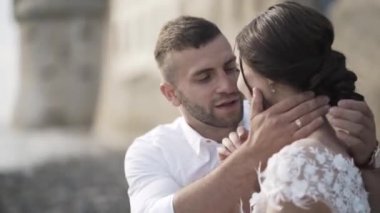 Şık beyaz gelinlik ve damat bankta oturan, gülümseyen ve öpüşme güzel masal gelin yakın çekim. Eylem. Bir hikaye kitabı düğün