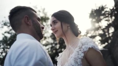 Parkta duran güzel mutlu düğün çiftinin yakından görünümü, arka planda ağaçların bulanık şekilleri ile gülümseyerek ve sarılma. Eylem. Bir hikaye kitabı düğün