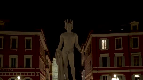Nude statue of man on background of buildings. Action. White statue of young poseidon stands on background of residential buildings at night — ストック動画