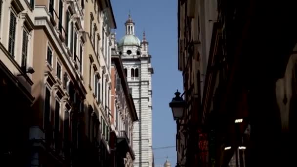 Part of Cathedral on background of houses. Action. Cathedral tower is visible from narrow street among residential buildings on blue sky background — Stock Video