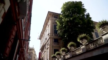 Bottom view of street with european old buildings. Action. Alley among old European houses and green vegetation in ancient pots