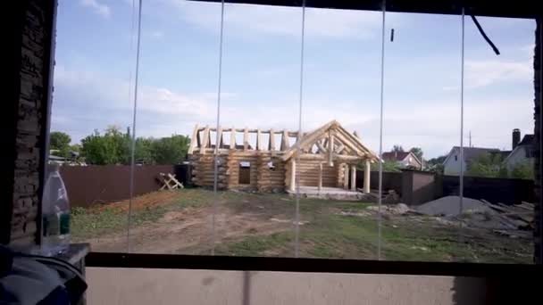 Wooden cottage in process of construction. Clip. View of wooden house without windows and roof in process of construction — ストック動画